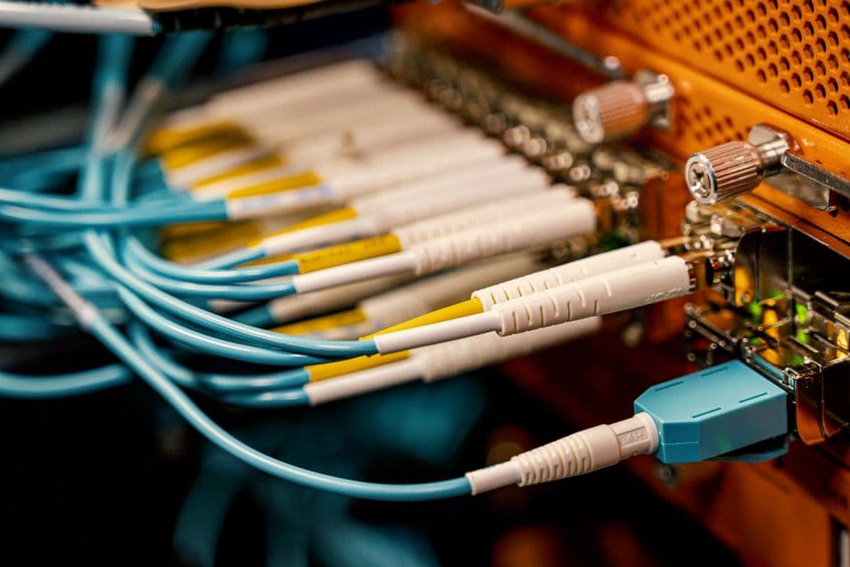 Módulo transceptor QSFP28 100G insertado en switch de datacenter de alta densidad con múltiples puertos y cables de fibra óptica conectados, mostrando el factor de forma estándar que permite 100 Gbps por puerto en infraestructuras de red modernas